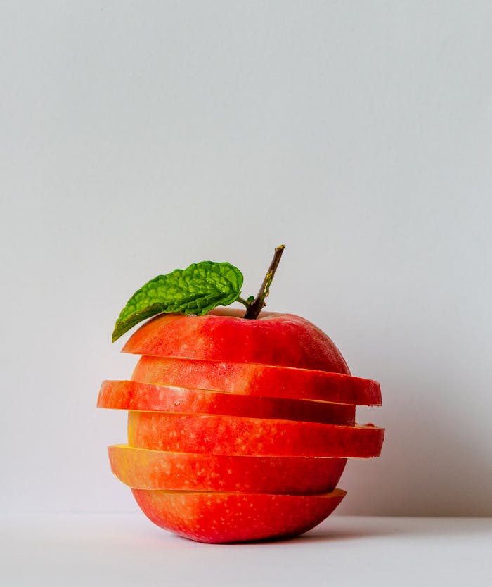 Artistic stack of sliced apple pieces with a fresh green leaf.